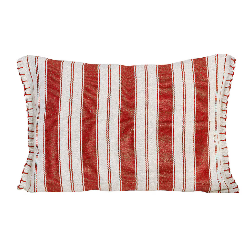Cojín rectangular con rayas rojas, botones decorativos y flecos. Estilo rústico artesanal sobre base clara.